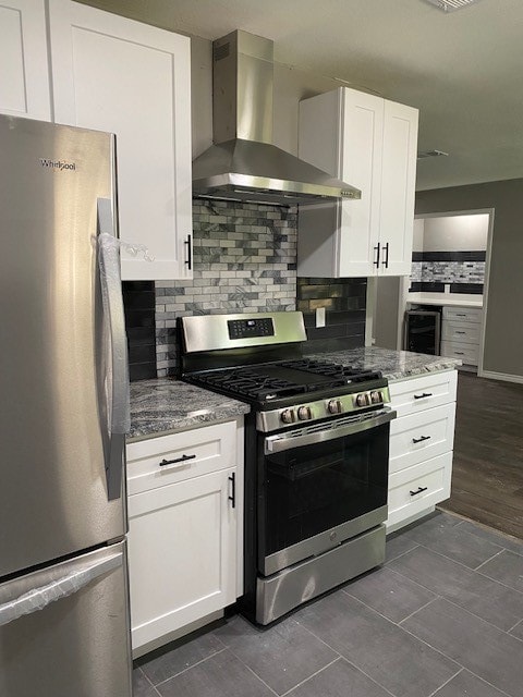 kitchen featuring stainless steel appliances, tasteful backsplash, stone countertops, white cabinets, and wall chimney range hood