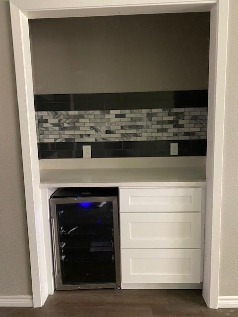 room details featuring wine cooler, a bar, and wood finished floors