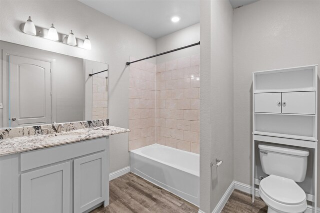 full bathroom featuring hardwood / wood-style floors, tiled shower / bath combo, toilet, and vanity