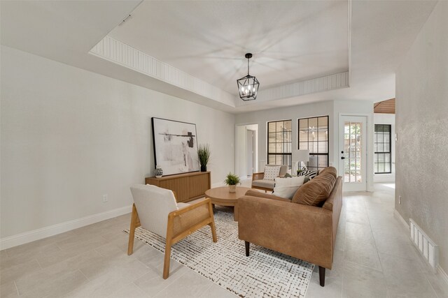 living room featuring a tray ceiling and a notable chandelier