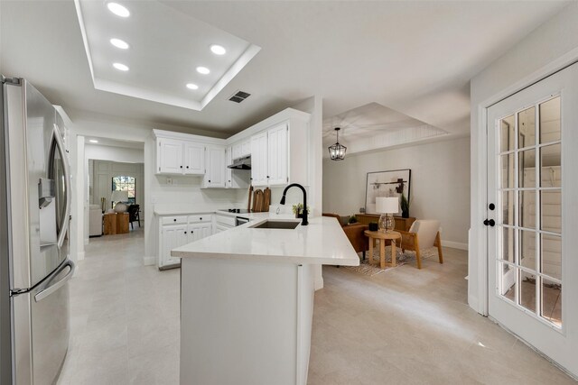 kitchen with a raised ceiling, sink, hanging light fixtures, stainless steel fridge with ice dispenser, and kitchen peninsula