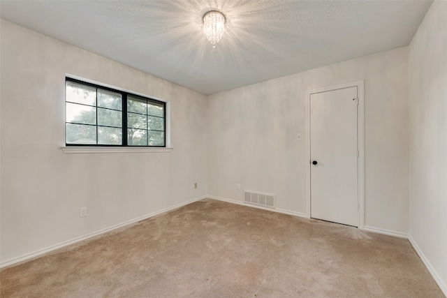 carpeted spare room with a chandelier