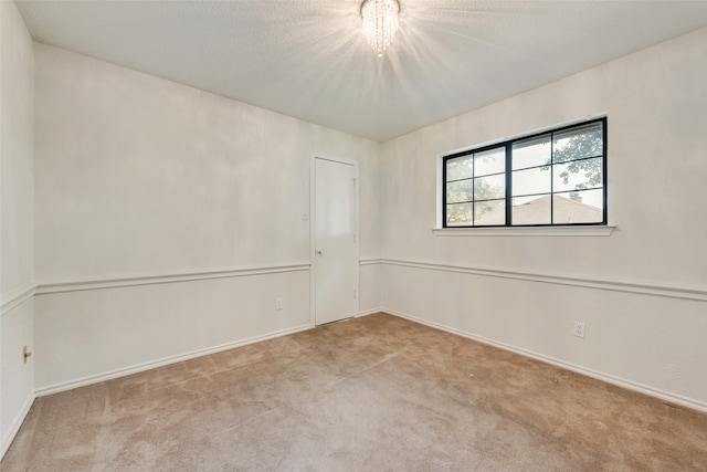 empty room featuring light carpet and a chandelier