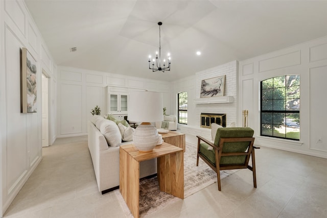 living room featuring a chandelier, vaulted ceiling, and a brick fireplace