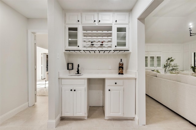 bar featuring white cabinets, light tile patterned floors, and sink