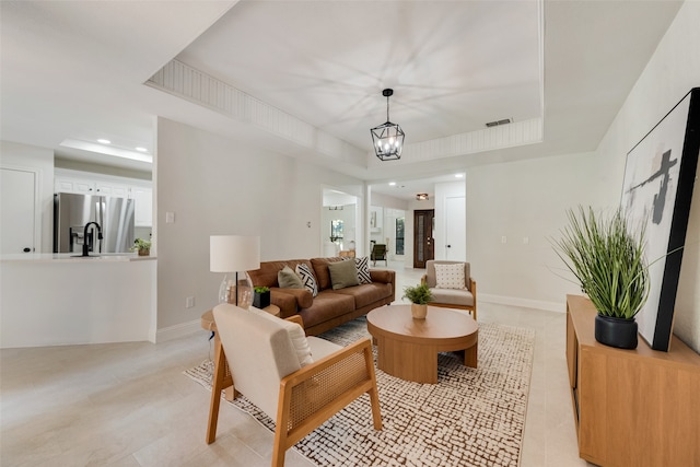 living room with a raised ceiling and a chandelier