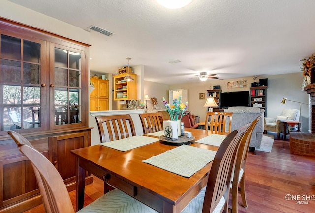 dining room featuring ceiling fan, dark hardwood / wood-style flooring, and a textured ceiling