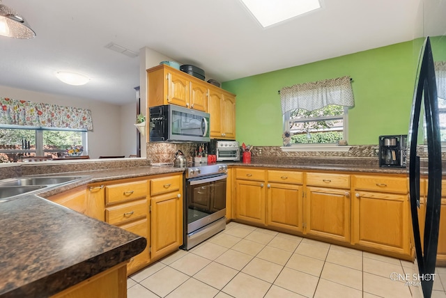 kitchen with appliances with stainless steel finishes, tasteful backsplash, light tile patterned floors, and a wealth of natural light