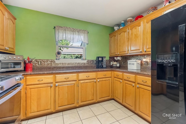 kitchen featuring light tile patterned flooring, black fridge with ice dispenser, stainless steel range, and tasteful backsplash