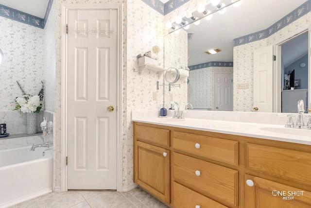 bathroom featuring tile patterned flooring, vanity, a tub, and a skylight