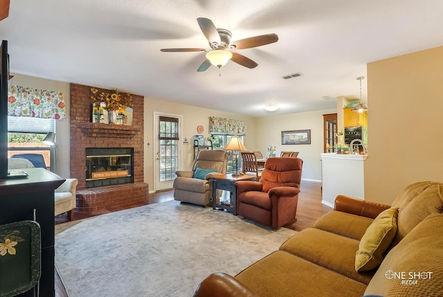 living room with ceiling fan, a fireplace, and light hardwood / wood-style floors