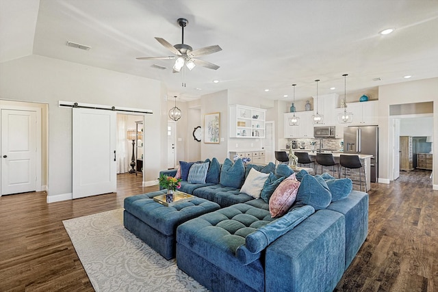 living room featuring a barn door, ceiling fan, dark wood-type flooring, and lofted ceiling