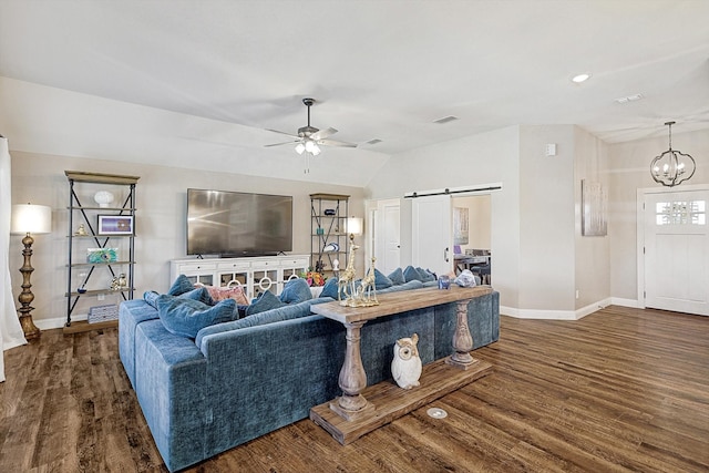 living room featuring a barn door, dark hardwood / wood-style flooring, ceiling fan with notable chandelier, and lofted ceiling