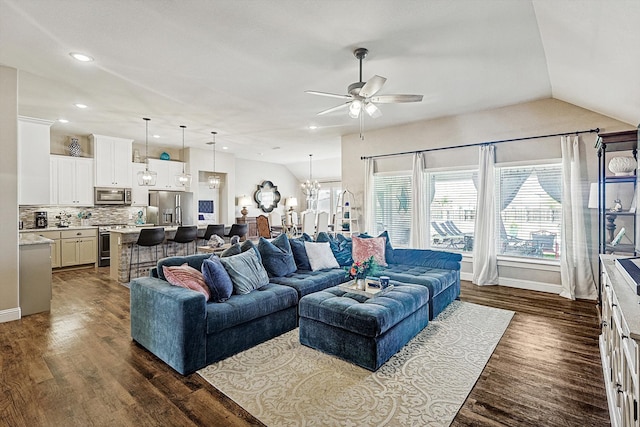 living room featuring ceiling fan with notable chandelier, dark hardwood / wood-style flooring, and vaulted ceiling