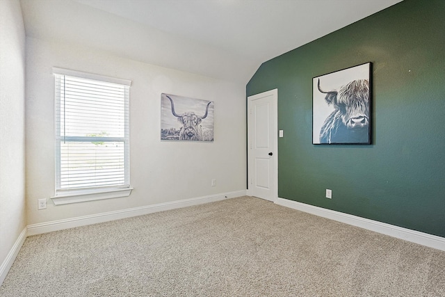 spare room with carpet floors and vaulted ceiling