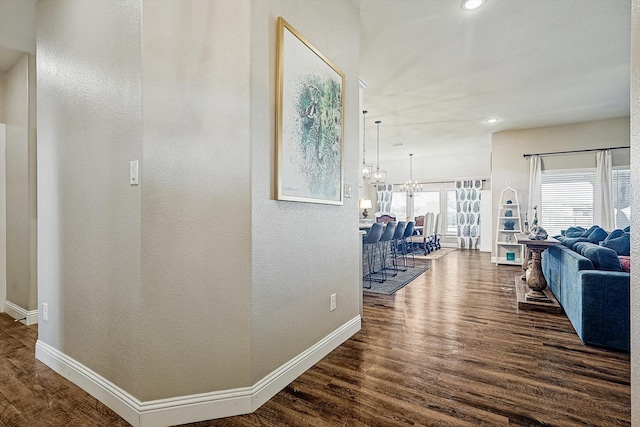 hall with dark hardwood / wood-style floors and a notable chandelier