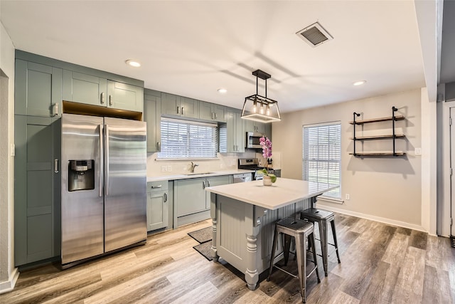 kitchen featuring pendant lighting, plenty of natural light, stainless steel appliances, and light hardwood / wood-style flooring