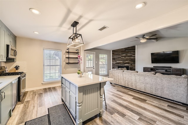 kitchen featuring a center island, lofted ceiling, hanging light fixtures, light hardwood / wood-style flooring, and appliances with stainless steel finishes