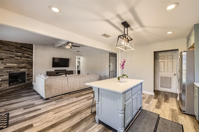 kitchen featuring a center island, lofted ceiling, hardwood / wood-style flooring, stainless steel fridge, and decorative light fixtures