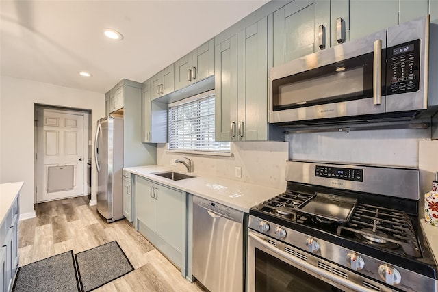 kitchen featuring gray cabinetry, sink, stainless steel appliances, and light wood-type flooring