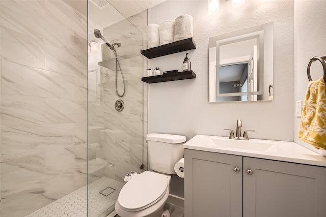 bathroom with toilet, a tile shower, and vanity