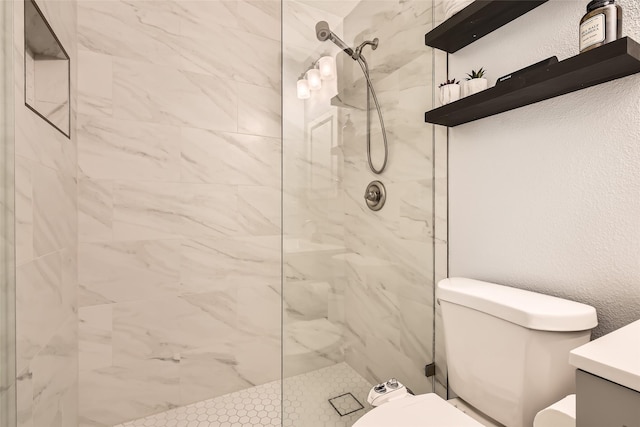 bathroom with vanity, toilet, and tiled shower