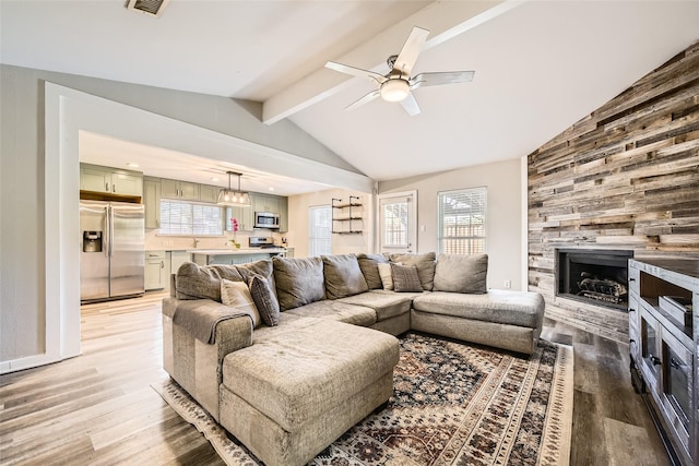 living room with a fireplace, lofted ceiling with beams, light hardwood / wood-style flooring, and ceiling fan