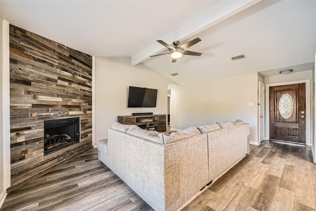 living room with lofted ceiling with beams, ceiling fan, wood-type flooring, and a fireplace