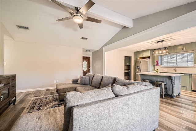 living room with lofted ceiling with beams, sink, ceiling fan, and light hardwood / wood-style floors