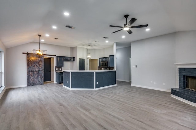 kitchen with decorative light fixtures, a kitchen island, ceiling fan, a barn door, and hardwood / wood-style floors