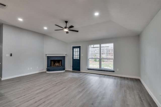 unfurnished living room featuring a brick fireplace, light hardwood / wood-style flooring, ceiling fan, and lofted ceiling