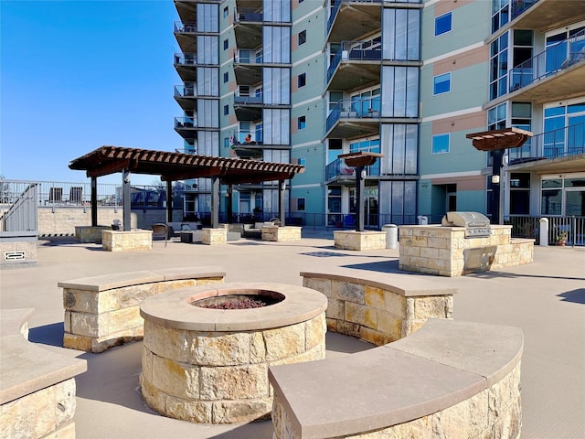 view of property's community with an outdoor kitchen, a pergola, and a fire pit