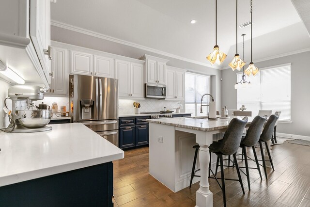 kitchen with white cabinets, stainless steel appliances, blue cabinetry, and a large island with sink