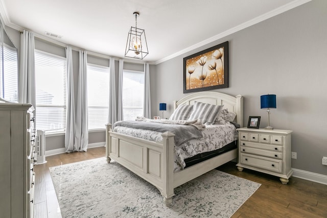 bedroom featuring dark wood-type flooring, ornamental molding, and an inviting chandelier