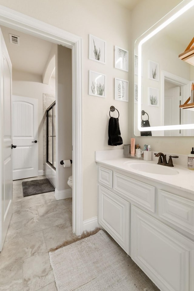 bathroom featuring vanity, a shower with shower door, and toilet