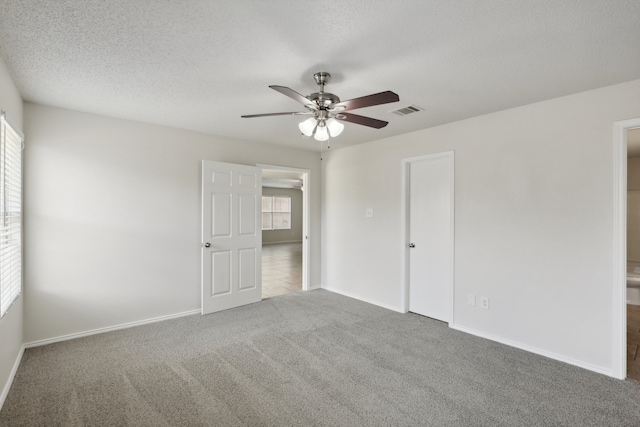 carpeted spare room featuring a textured ceiling and ceiling fan