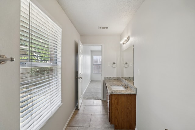 bathroom with a textured ceiling, vanity, and tile patterned floors