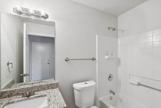 full bathroom with vanity, a textured ceiling, toilet, and shower / washtub combination