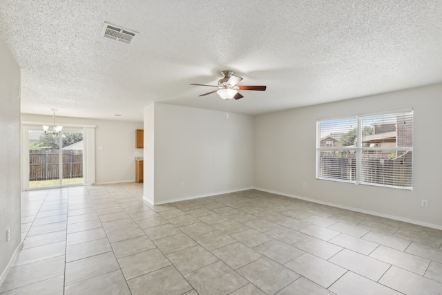 empty room with a wealth of natural light, light tile patterned flooring, ceiling fan with notable chandelier, and a textured ceiling