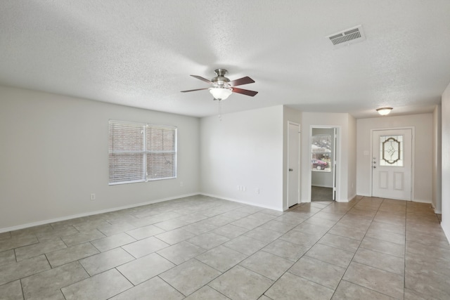 tiled empty room featuring a wealth of natural light and a textured ceiling