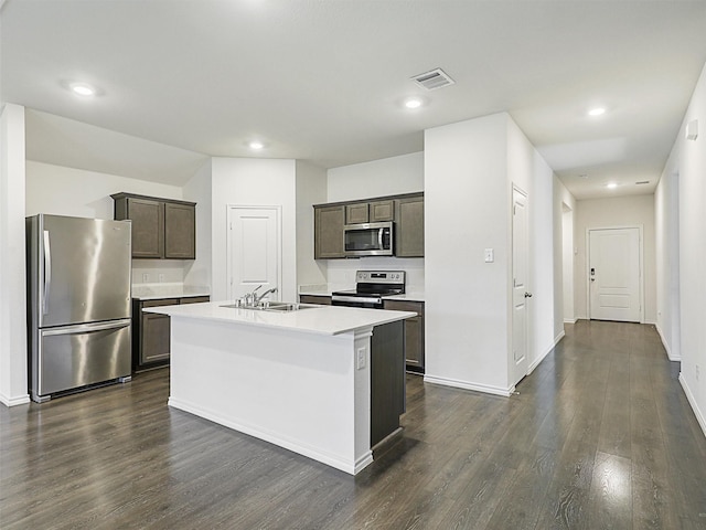 kitchen featuring appliances with stainless steel finishes, dark hardwood / wood-style flooring, dark brown cabinetry, sink, and a center island with sink