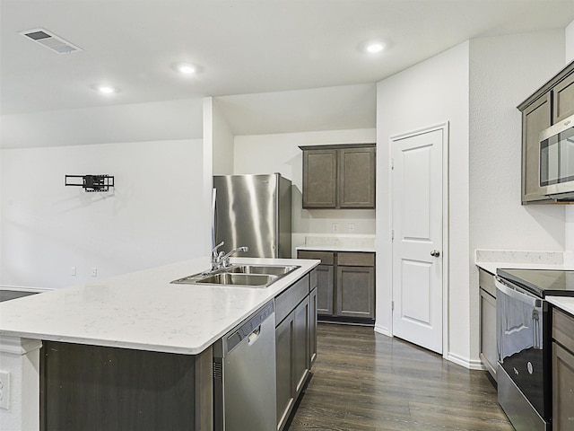 kitchen with dark wood-type flooring, stainless steel appliances, a center island with sink, and sink