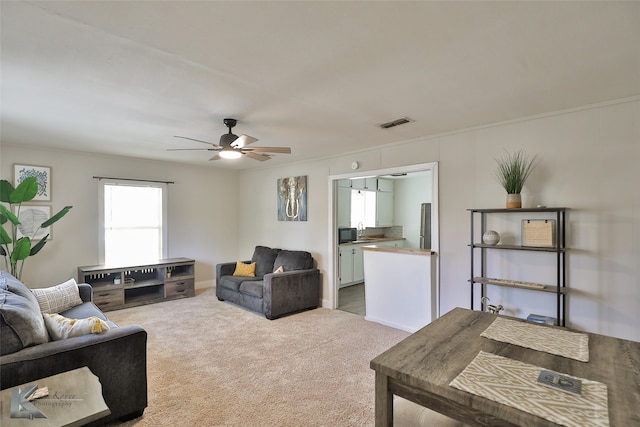 carpeted living room featuring ceiling fan and sink