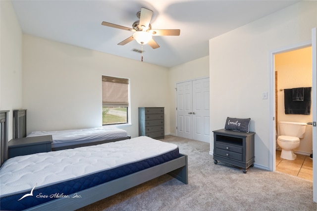 carpeted bedroom featuring ceiling fan, ensuite bath, and a closet