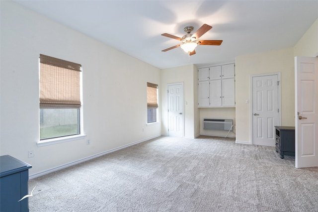 unfurnished bedroom featuring light carpet, an AC wall unit, ceiling fan, and multiple closets