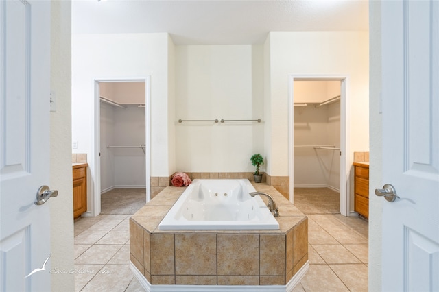 bathroom featuring tile patterned flooring, vanity, and tiled tub