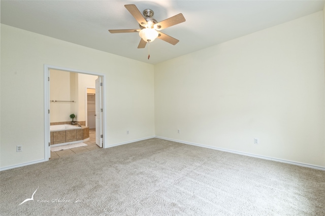 unfurnished bedroom with ceiling fan, light colored carpet, and ensuite bath