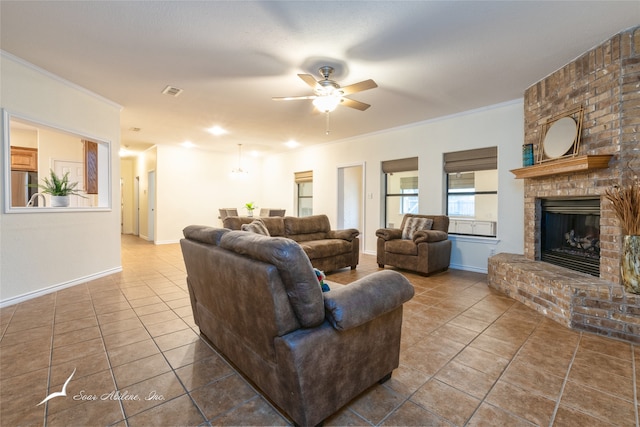 living room with tile patterned floors, ceiling fan, crown molding, and a brick fireplace