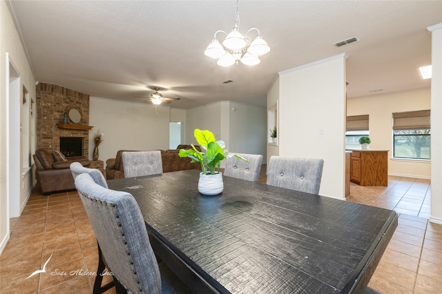 dining area featuring a fireplace, light tile patterned floors, and ceiling fan with notable chandelier