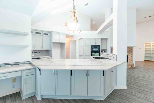 kitchen with black appliances, light stone countertops, hanging light fixtures, and hardwood / wood-style flooring